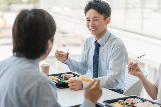 社員食堂でランチ・仕出し弁当・デリバリー・ケータリングの弁当を食べる男女（福利厚生）
