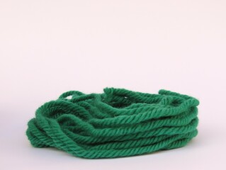 Green wool yarn for knitting on white background.