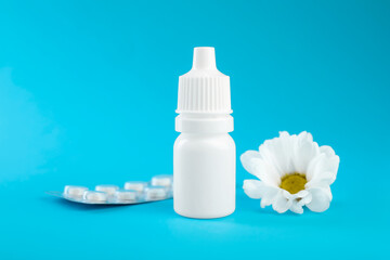 Allergy treatment. Nasal drops, pills and flower on light blue background, closeup