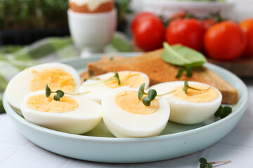 Cut hard boiled eggs with bread on white tiled table, closeup