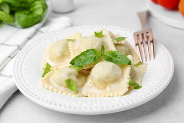 Delicious ravioli with cheese and basil served on light table, closeup