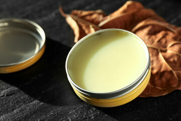 Natural solid perfume and dry leaf on black table, closeup