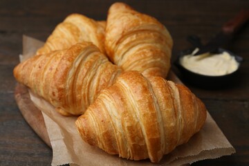 Tasty fresh croissants served with butter on wooden table, closeup