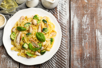 Delicious pasta Alfredo with chicken served on wooden table, flat lay. Space for text