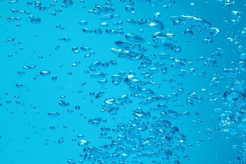 Many water bubbles on blue background, closeup