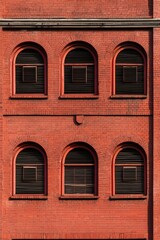 Fototapeta premium Red brick building facade, symmetrical arched windows. Urban architectural detail