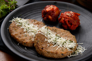 grilled meatballs with kimchi and cheese on a black plate