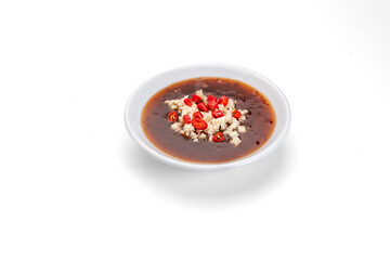 Thai Sukiyaki Sauce in a small cup, sprinkled with chopped chili and minced garlic.