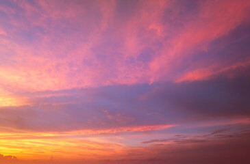Obraz premium Colorful sunset sky with setting sun behind vivid orange and yellow clouds