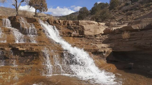 TOQUERVILLE FALLS, UTAH, USA - February 07, 2025: Aerial-Ascending-View of waterfall over sandstone ledges to top of the falls