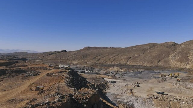 HURRICANE, UTAH, USA - February 07, 2025:Aerial-Flying over the rim of a igneous basalt cliff face to reveal a gravel pit operation on the banks of the Virgin River