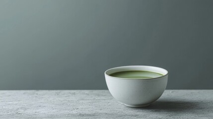 Minimalist white ceramic bowl of green tea on gray surface