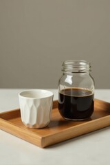 Aromatic Dark Brew in a Glass Jar Served with a White Cup on a Wooden Tray