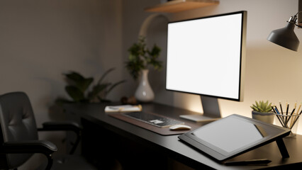 A side view of the white screen computer with graphic tablet and decorative items on wooden table.