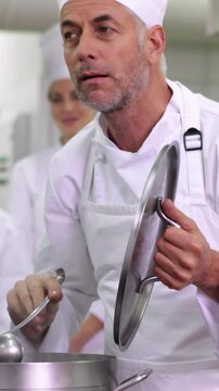 Head chef tasting pot of soup making ok sign