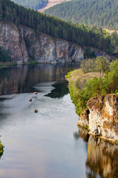 picturesque view of the Belaya River, the South Ural taiga, tourists rafting from the Insebika cliff on a summer day