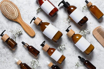 Composition with bottles of shampoo, hair brush and gypsophila flowers on white grunge background