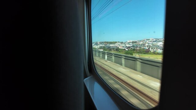View of the japanese countryside from the window of a high speed train traveling on a bridge