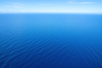 Obraz premium Aerial view of calm deep blue ocean with light blue sky and wavy ocean floor