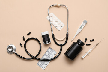 Composition with pulse oximeter, stethoscope, thermometer and medicines on beige background