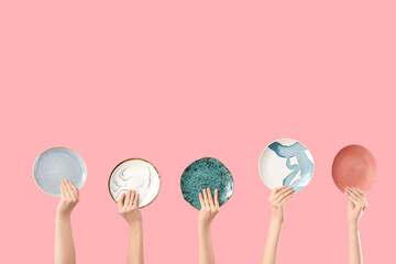 Female hands with different plates on pink background