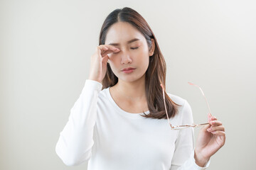 Eye problem concept, fatigue asian young woman tired eyes irritated rubbing, massage eye dry relief vision pain after work, eye strain, hand holding glasses, suffer bad blurry isolated on background.