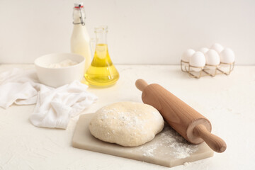 Wooden rolling pin, dough and ingredients on white background
