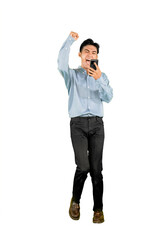 Excited Young Man Celebrating Success with Smartphone on White Background