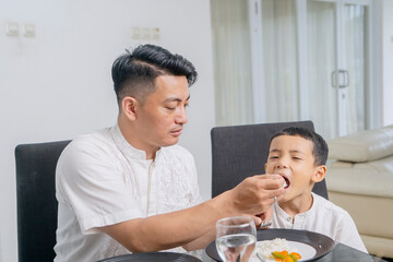 Caring Muslim Father Feeding His Son During Family Mealtime