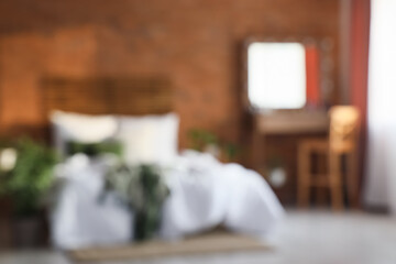 Blurred view of bedroom with dressing table and bed near brick wall