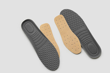 Different orthopedic insoles on light background, top view