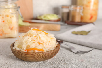 Tasty sauerkraut in wooden plate on white table. Closeup