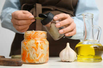 Woman taking bay leaf from jar on table in kitchen. Closeup