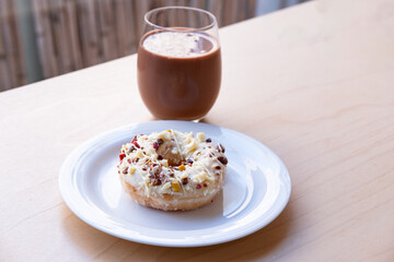 Iced Ring Doughnut on a White Plate Against a Wooden Background