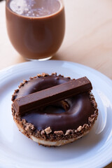 Iced Ring Doughnut on a White Plate Against a Wooden Background