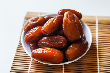 Dates fruit in small white bowl isolated on white background. (Kurma)