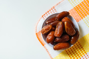 Dates fruit in small white bowl isolated on white background. (Kurma)