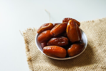 Dates fruit in small white bowl isolated on white background. (Kurma)