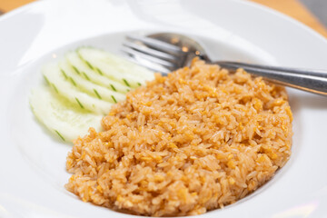 Fried Rice served in a bowl egg, vegetable, delicious thai dish like savory meal lunch. Plate of fried-rice cucumber as garnish, Asian cuisine nasi goreng a traditional indonesian breakfast or dinner.