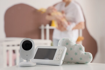 Baby monitor on table against mother with her child in bedroom, closeup