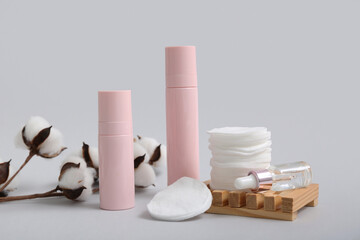 Set of cosmetic products, pads and cotton branch on grey background