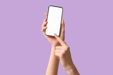 Female hands holding modern mobile phone on purple background, closeup
