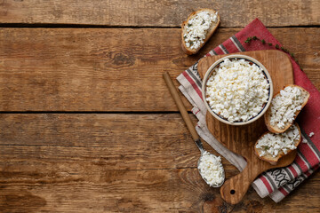 Bowl with fresh cottage cheese and bread slices on wooden background