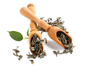 Wooden scoops with dried green tea leaves on white background