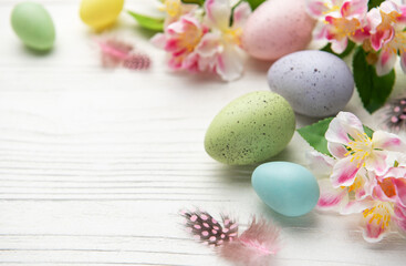 Colorful easter eggs and spring flowers creating festive border on white wood
