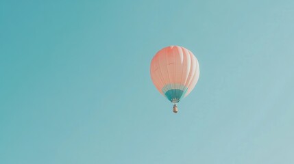 Fototapeta premium Pastel pink and blue hot air balloon floats in a clear sky.