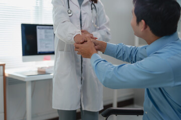 Doctor holding hands of patient in wheelchair, providing empathy and support during medical...