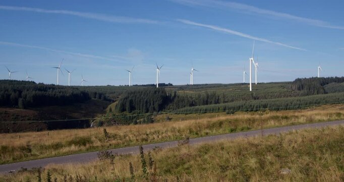 Extra Wide shot of multiple wind turbines rotating with blue sky on the A A4061 at Hendre'r Mynydd Car Park,