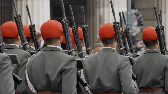 Professional servicemen with machine guns walk on parade. Young soldiers hold weapons near shoulders going in ranks during festive march to celebrate Austrian Independence Day