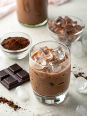 Iced Chocolate Indulgence: An inviting view of an iced chocolate drink, surrounded by components like ice cubes, chocolate powder, chocolate and a bottle to complete the image of a delicious beverage.